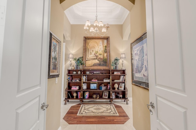 corridor featuring light tile patterned floors, a tray ceiling, ornamental molding, and a chandelier