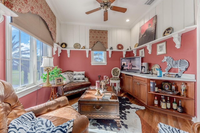 living room with ceiling fan, ornamental molding, a healthy amount of sunlight, and wood-type flooring