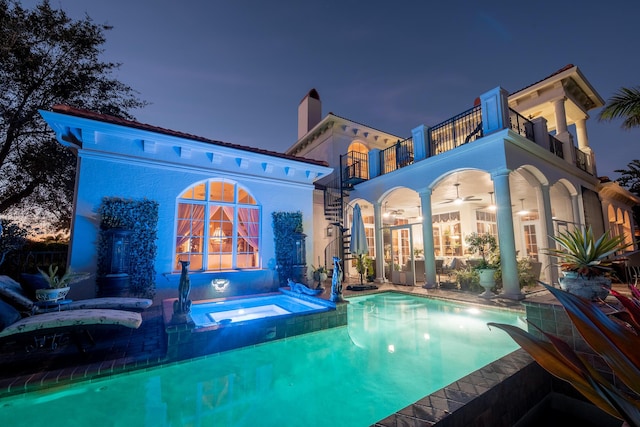 rear view of house featuring a swimming pool with hot tub, a patio, a balcony, and ceiling fan