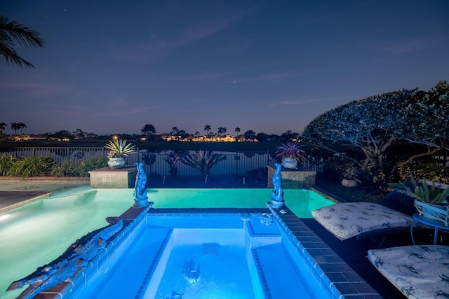 pool at dusk featuring an in ground hot tub