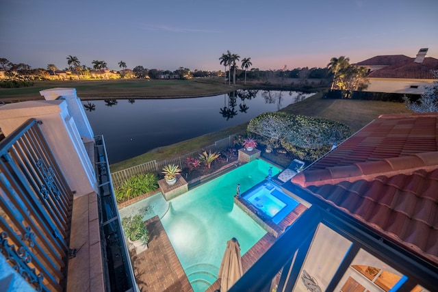 pool at dusk featuring an in ground hot tub and a water view