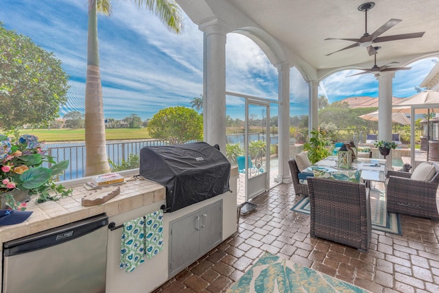 sunroom / solarium featuring plenty of natural light, ceiling fan, and a water view