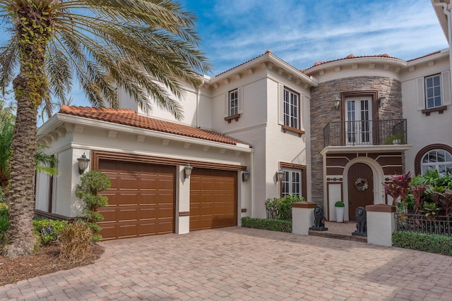 mediterranean / spanish house with a garage, a balcony, and french doors