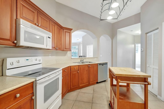 kitchen with sink, white appliances, and light tile flooring