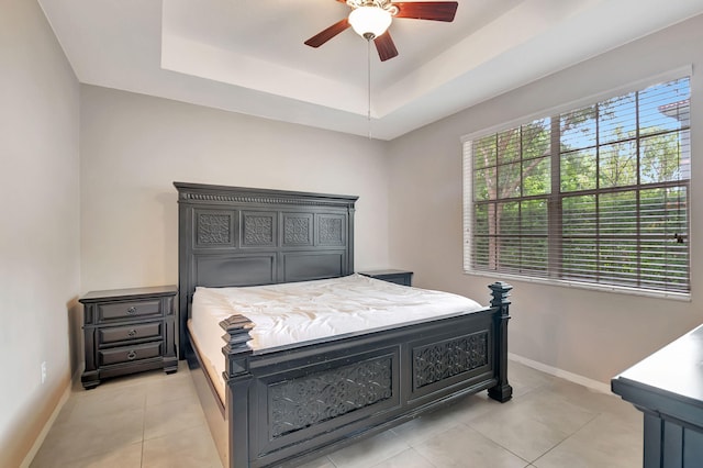 bedroom with ceiling fan, a raised ceiling, and light tile floors