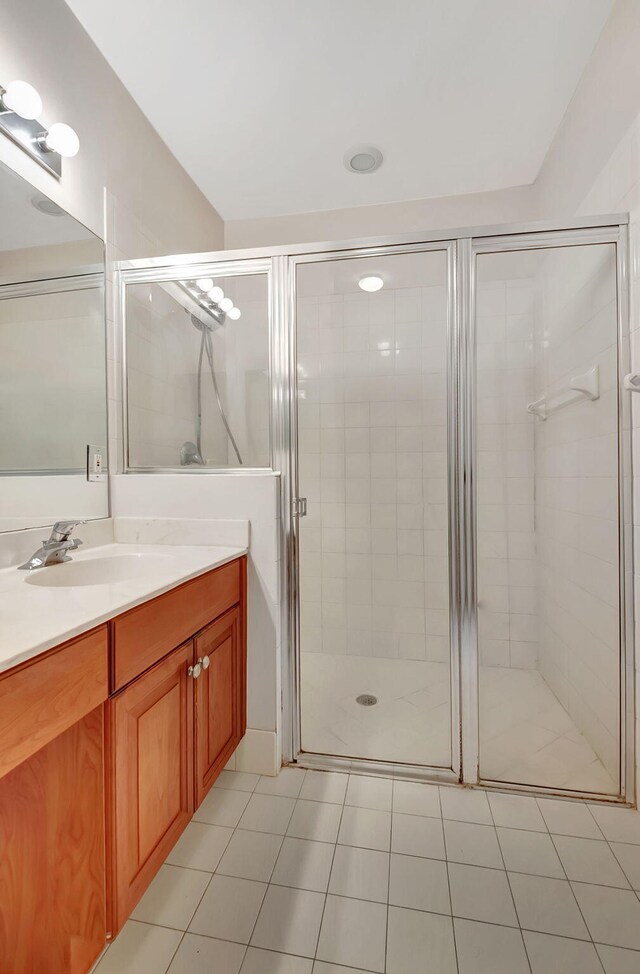 bathroom featuring tile floors, a shower with door, and vanity with extensive cabinet space