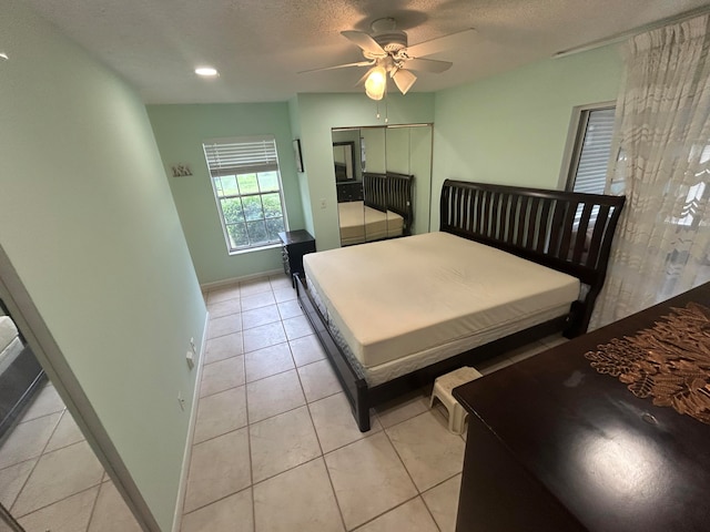 bedroom with a textured ceiling, ceiling fan, and light tile floors