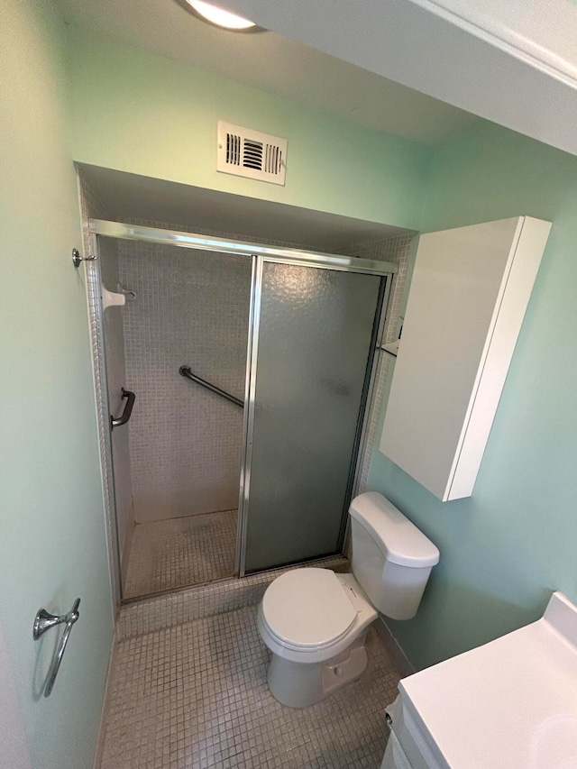 bathroom featuring tile flooring, vanity, toilet, and a shower with door