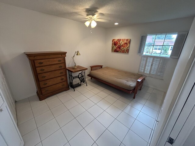 bedroom featuring a textured ceiling, ceiling fan, and light tile floors