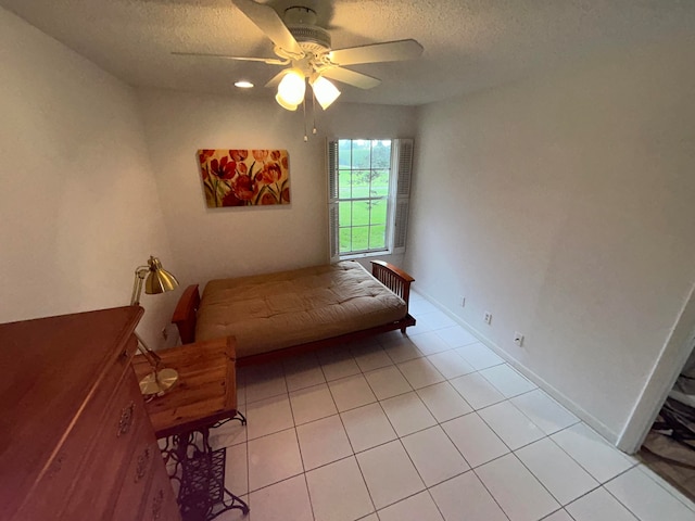 unfurnished bedroom featuring a textured ceiling, ceiling fan, and light tile floors