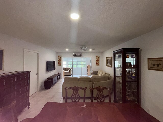 living room with a textured ceiling, light tile flooring, and ceiling fan