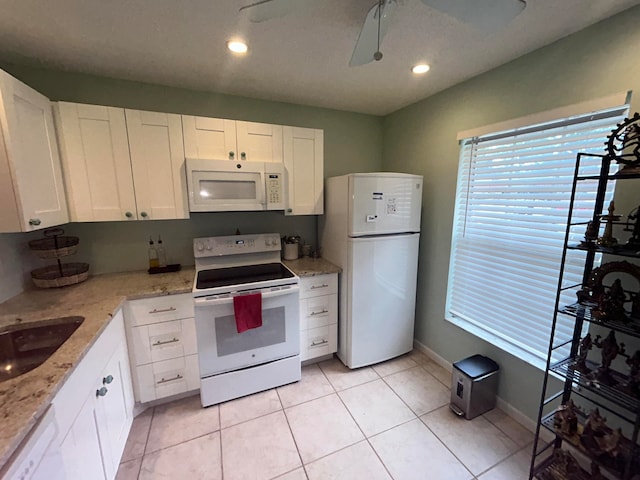 kitchen with light stone counters, white appliances, white cabinets, and light tile floors