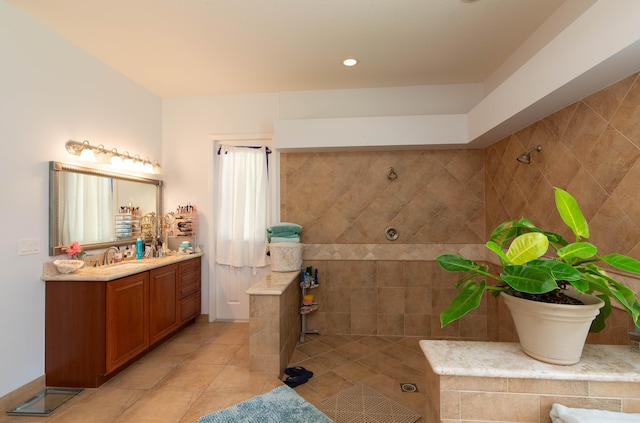 bathroom featuring tile patterned flooring, a tile shower, and vanity