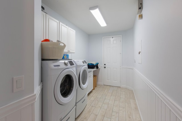 laundry area with cabinets, washer and clothes dryer, and light hardwood / wood-style flooring