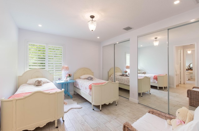 bedroom featuring light hardwood / wood-style floors and two closets