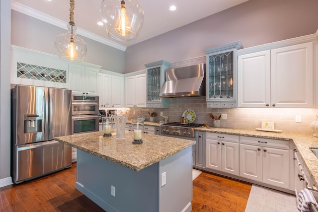 kitchen with pendant lighting, wall chimney range hood, white cabinets, and stainless steel appliances