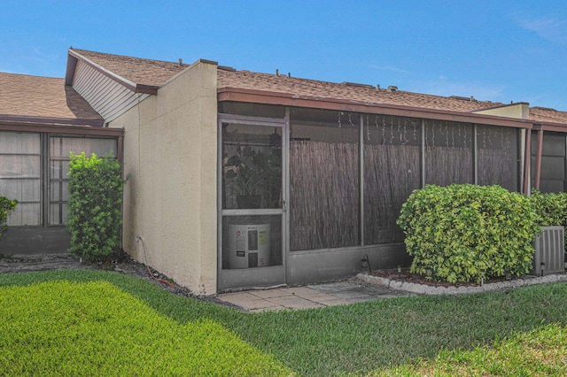 view of exterior entry with a lawn and central air condition unit