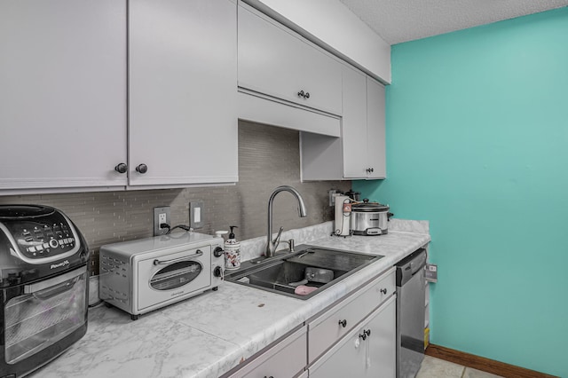 kitchen featuring stainless steel dishwasher, a textured ceiling, white cabinets, sink, and light tile floors