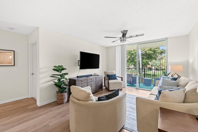 127 Yacht Club Way Unit 206, Hypoluxo, FL 33462 - living room featuring a textured ceiling, baseboards, light wood-style flooring, and a ceiling fan
