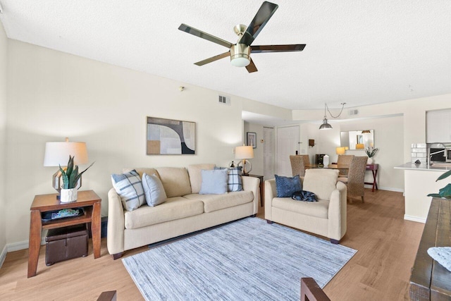 127 Yacht Club Way Unit 206, Hypoluxo, FL 33462 - living room with a ceiling fan, light wood-style floors, visible vents, and a textured ceiling
