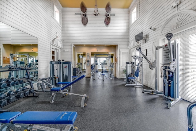 127 Yacht Club Way Unit 206, Hypoluxo, FL 33462 - exercise room featuring wood walls, visible vents, and a towering ceiling