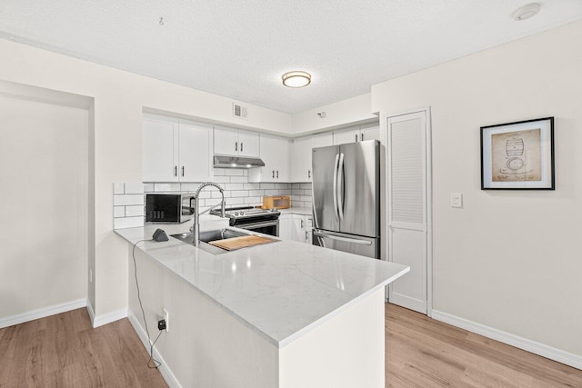 127 Yacht Club Way Unit 206, Hypoluxo, FL 33462 - kitchen with under cabinet range hood, appliances with stainless steel finishes, visible vents, and light wood finished floors