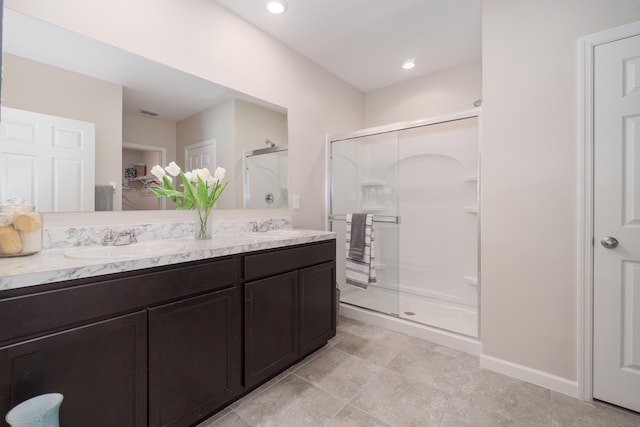 bathroom featuring a shower with shower door and vanity