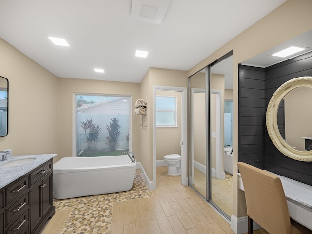 bathroom featuring a tub to relax in, hardwood / wood-style flooring, vanity, and toilet