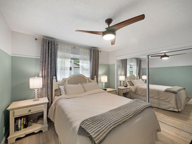 bedroom featuring ceiling fan, light hardwood / wood-style floors, and a textured ceiling