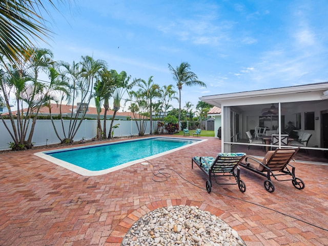 view of swimming pool featuring a patio area and a sunroom