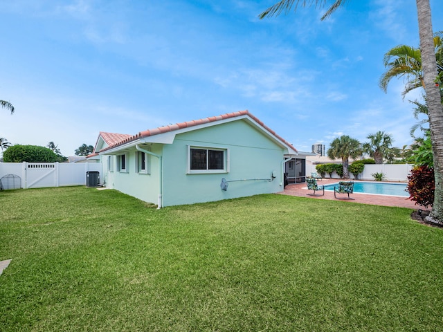 back of house featuring a yard, a fenced in pool, and central air condition unit