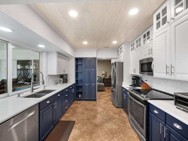 kitchen with appliances with stainless steel finishes, tasteful backsplash, blue cabinets, sink, and white cabinets