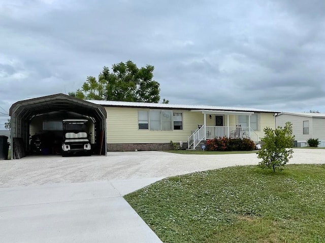 manufactured / mobile home featuring a front lawn, a carport, and covered porch