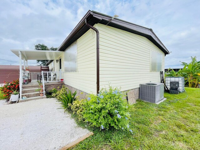 view of side of home featuring central air condition unit and a yard