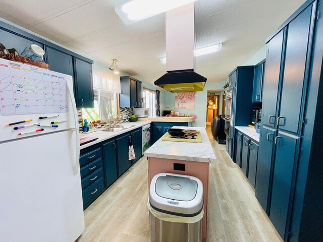 kitchen featuring island exhaust hood, white appliances, blue cabinetry, light wood-type flooring, and sink