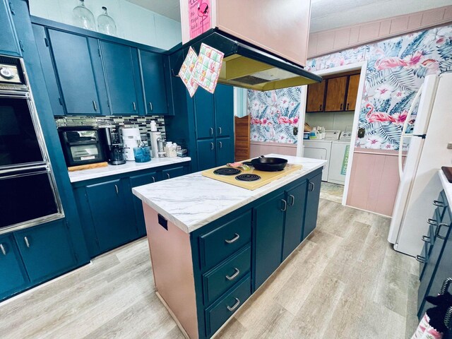 kitchen featuring a kitchen island, light wood-type flooring, white appliances, blue cabinetry, and washing machine and dryer