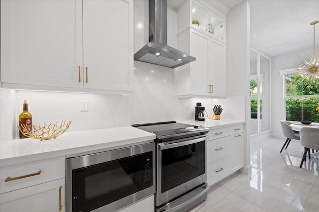 kitchen with wall chimney range hood, pendant lighting, white cabinetry, black microwave, and stainless steel electric stove