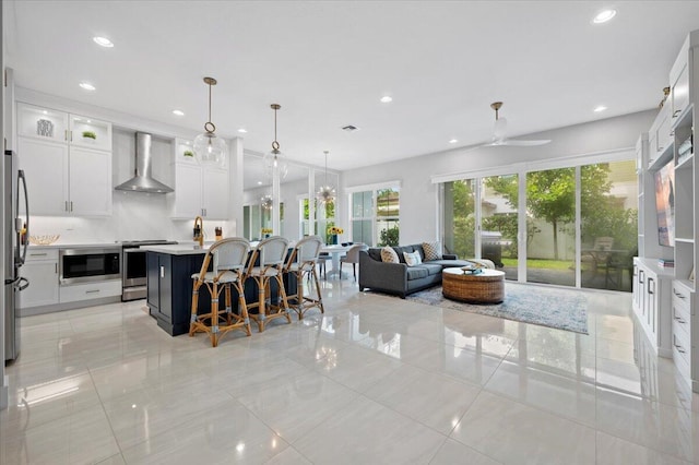 kitchen with white cabinetry, wall chimney exhaust hood, hanging light fixtures, and a center island