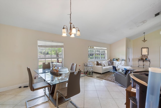 tiled dining space with lofted ceiling, plenty of natural light, and an inviting chandelier