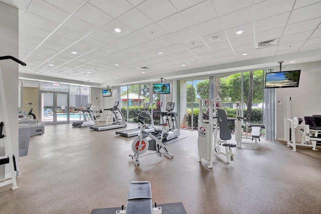 exercise room with plenty of natural light, expansive windows, and a drop ceiling