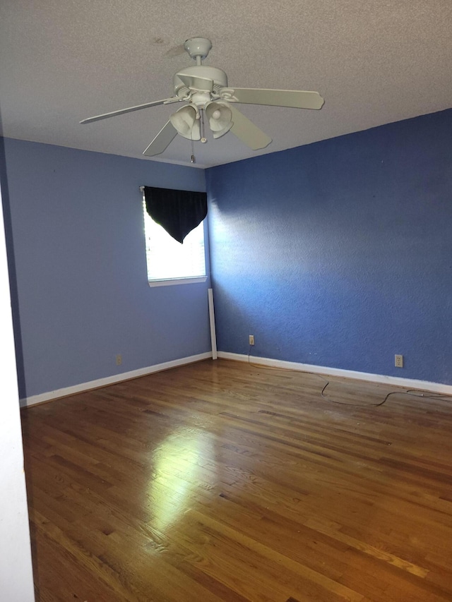 empty room with ceiling fan, wood-type flooring, and a textured ceiling