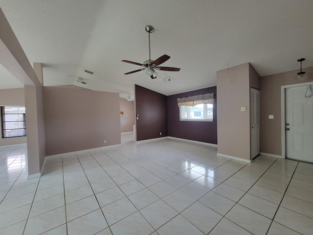 tiled empty room with ceiling fan, a textured ceiling, and vaulted ceiling