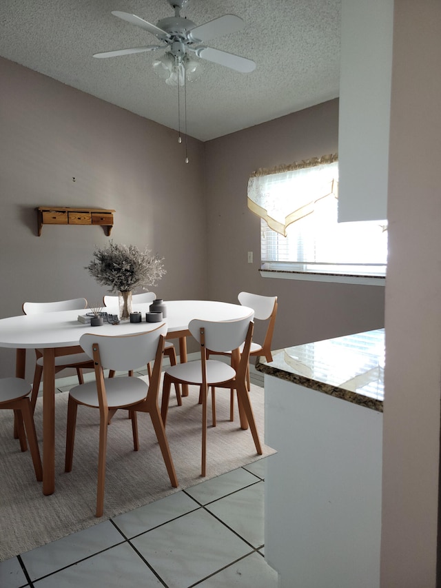 dining room with ceiling fan, light tile patterned flooring, and a textured ceiling