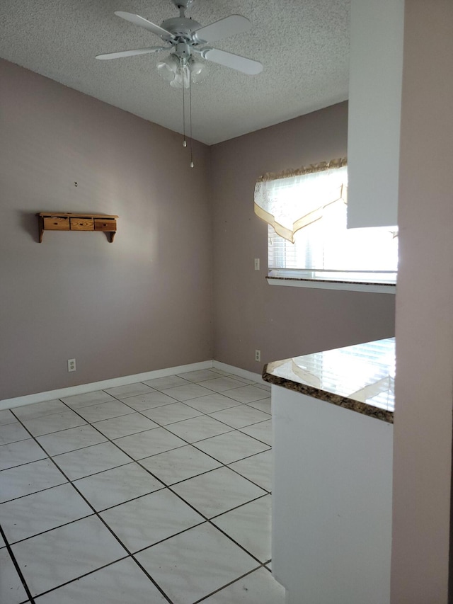 tiled spare room with a textured ceiling and ceiling fan