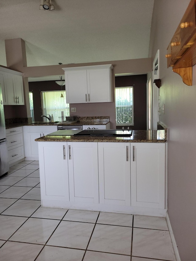 kitchen with white cabinetry, kitchen peninsula, and stainless steel refrigerator