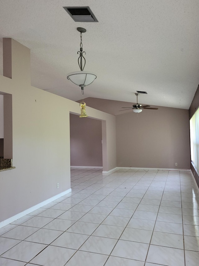 spare room featuring vaulted ceiling, ceiling fan, light tile patterned flooring, and a textured ceiling