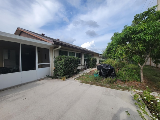 view of property exterior with a sunroom and a patio area