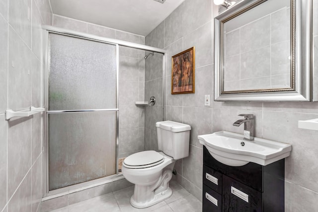 full bath with tile patterned flooring, vanity, toilet, tile walls, and a shower stall