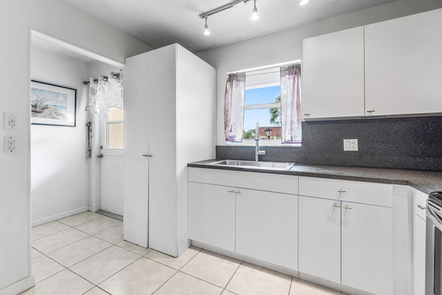 kitchen with a sink, dark countertops, white cabinets, and light tile patterned flooring