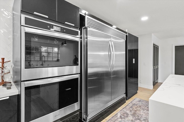 kitchen featuring light stone counters, light hardwood / wood-style flooring, and stainless steel appliances